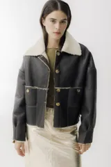 Campera de cuero negro con interior de piel sintética, cuello solapa, cierre frontal con botones y bolsillos delanteros.