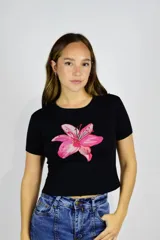 Remera negra corta de algodón, con mangas cortas y estampa frontal de una flor rosada grande.