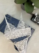 Conjunto de lencería compuesto por un top bralette y una tanga colaless, ambos confeccionados en encaje floral blanco con detalles de breteles regulables.