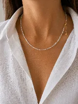 Collar de cuentas pequeñas transparentes tipo cristal, con cierre y cadena de alargue dorada que finaliza en un pequeño dije de corazón.