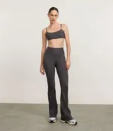 Pantalón deportivo femenino de microfibra, color gris oscuro, modelo flare (campana) con cintura alta. Presenta costuras visibles en contraste.