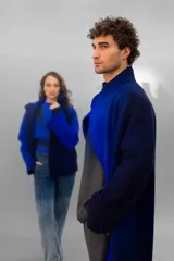 Tapado oversize desestructurado de lana merino afieltrada, teñido en degradé azul y negro. Tiene bolsillos laterales, cierre con broches ocultos y puños amplios que cubren la mano.