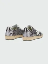Zapatillas Golden Goose modelo Ballstar, con cuerpo cubierto de glitter negro y plateado, puntera laminada en tono oscuro, estrella lateral blanca y suela de aspecto desgastado.