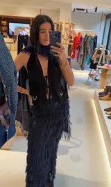 Chaleco negro de cuero con escote halter profundo, cierre frontal con lazos y bolsillos aplicados con detalles metálicos.
