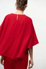 Vestido corto rojo de cuello redondo y manga corta tipo capa. Cierre en la espalda con abertura y botón.