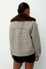 Campera de sarga a cuadros en tonos beige, marrón y gris, con acabado cepillado. Diseño de corte holgado con cuello extraíble de efecto peludito en color marrón oscuro, cierre frontal con botones, canesú en la espalda, hombros caídos, puños abotonados y bolsillos delanteros con solapa y botón. Forrada.