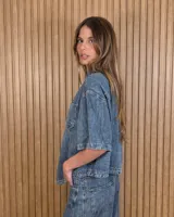 Sobrecamisa de denim soft azul, con cuello clásico, mangas cortas amplias, bolsillos frontales con solapa y cierre de botones metálicos.