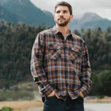 Camisa de manga larga Maui and Sons con estampado de cuadros escoceses en tonos marrones y azules. Presenta cuello clásico, cierre frontal con botones y dos bolsillos delanteros con solapa.