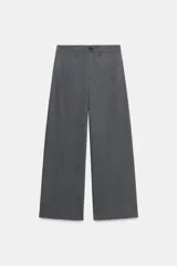 Pantalón de tiro medio color gris, con corte recto, bolsillos delanteros y detalle de costura vertical en el frente. Cuenta con cierre frontal de cremallera y botón.