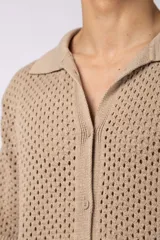 Camisa de punto calado en color beige, de manga corta y corte relajado. Presenta cuello tipo bowling, cierre frontal con botones al tono y una estructura liviana y respirable confeccionada en algodón.