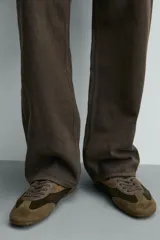 Zapatilla de cordones confeccionada en piel con acabado de serraje en tonos marrones. Presenta un diseño de perfil bajo con suela ultrafina a contraste y detalle de pespuntes decorativos.