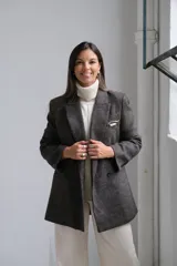 Blazer de corte sastrero en color gris oscuro con textura jaspeada. Presenta solapas clásicas, cierre frontal de doble botonadura y un bolsillo superior con detalle de pañuelo decorativo.