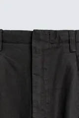 Pantalón de corte wide fit confeccionado en algodón con efecto lavado. Presenta pliegues frontales, bolsillos laterales y bolsillos traseros de vivo. Cierre frontal con cremallera y gancho metálico oculto.