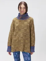 Pullover de punto jacquard color tostado con cuello alto y puños acanalados en tono azul y detalles en naranja. Cuenta con aberturas laterales y calce holgado.