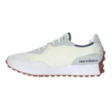 Championes urbanos New Balance modelo 327, de diseño retro en tonos gris, blanco off-white y azul marino, con suela dentada de goma marrón que se extiende hacia el talón y el característico logotipo "N" grande en el lateral.