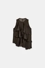 Top de cuello redondo y manga sisa, confeccionado en tejido con acabado satinado. Presenta volantes en cascada y un diseño de bajo asimétrico, con cierre en la espalda mediante pequeña abertura y botón.