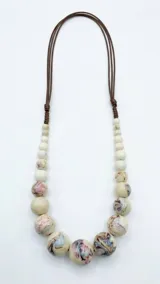 Collar de cuentas de cerámica celestes con diseño marmoleado y detalles oscuros, con cordón marrón regulable.