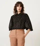 Blusa negra de chiffon con estampado de mini íconos en color crema, cuello mao, solapa frontal con botones y mangas largas abullonadas.