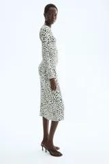 Vestido midi entallado de punto con estampado de leopardo, cuello redondo, manga larga y espalda descubierta con detalle cruzado en la cintura.