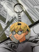 Llavero redondo con ilustración de Chifuyu Matsuno, personaje del anime Tokyo Revengers, con cabello rubio, anteojos y aretes dorados.