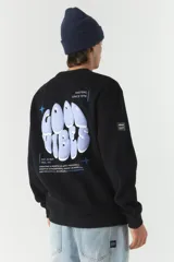 Buzo de felpa color crudo con cuello redondo y estampado frontal con el texto 'Good Vibes' y el logo de la marca Mistral. Tiene un parche con el logo de la marca en la manga izquierda.