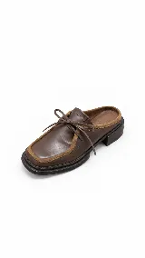 Zueco de cuero marrón con punta cuadrada, detalles de gamuza en los bordes y cordones de cuero ajustables en la parte superior.