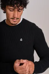 Sweater de punto grueso con cuello redondo, manga larga y puños acanalados. Presenta un pequeño logo bordado en el pecho.
