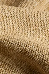 Bolso de playa tipo tote de tejido texturizado en color beige, con dos asas superiores para llevar al hombro.