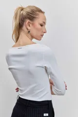 Remera de manga tres cuartos, color blanco, con cuello redondo y ajuste al cuerpo.