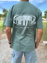 Remera oversize verde militar con estampado gráfico en la espalda con el texto "TOPSTYLE COLLECTIONS EST 2021".