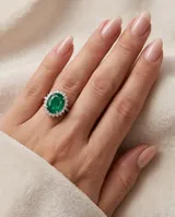 Anillo de plata con piedra central tallada en corte ovalado de color verde esmeralda, rodeada por un pavé de pequeñas circonias brillantes.