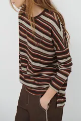 Remera de manga larga con diseño de rayas horizontales en tonos marrones, beige y rojizos. Presenta cuello redondo y un detalle bordado en el pecho.