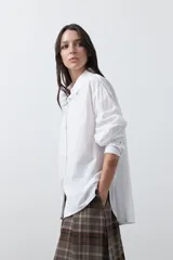 Camisa de corte relajado y diseño clásico, confeccionada en tela de algodón color celeste. Presenta cuello tradicional, cierre frontal con botones y mangas largas con puños rectos.