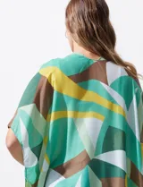 Kimono tejido de poliéster con estampado geométrico en tonos verde, amarillo, blanco y marrón. Presenta mangas amplias tipo japonesa y terminación de ruedo con borlas.