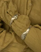 Brazalete rígido de diseño orgánico con textura irregular y acabado brillante, elaborado artesanalmente en metales nobles.