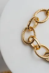 Pulsera dorada de eslabones grandes, algunos texturizados y otros lisos, con cierre de mosquetón y cadena de extensión.