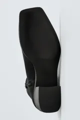 Bota corta color marrón de piel con acabado serraje, cierre de cremallera lateral, horma cuadrada y tacón de 5 cm.