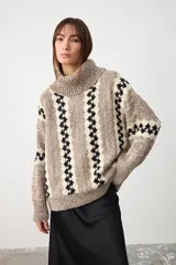 Sweater de punto con cuello tortuga, diseño holgado y estampado de rayas verticales con patrón geométrico en tonos beige, marrón y negro.