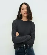 Blusa básica de manga larga con cuello redondo y puños ajustados, confeccionada en tejido de algodón y poliéster. Presenta un corte regular anatómico y diseño liso sin estampas.