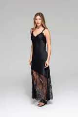 Vestido largo de seda color rojo, con escote en V y breteles finos. Presenta detalles de encaje en el escote y un diseño asimétrico en la falda que incorpora encaje transparente desde la altura de la rodilla.