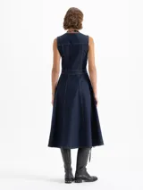 Vestido largo de denim azul oscuro, sin mangas, con cuello mao y cierre frontal de botones. Presenta dos bolsillos con solapa en el pecho y costuras decorativas. La falda es acampanada.