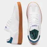 Championes Joma modelo Campus, color blanco con suela de goma color caramelo. Presentan detalles en cuero sintético y un refuerzo en el talón de color verde azulado oscuro.