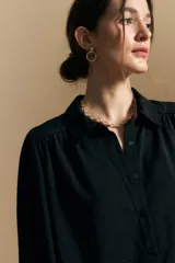 Camisa de manga larga con caída fluida, diseño de silueta suelta, cuello clásico y cierre frontal con botones.