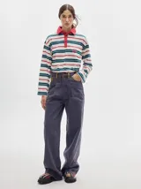 Pantalón jean de tiro alto y corte pinzado, con perneras de caída suelta y levemente anchas en el bajo. Posee pasador con hebilla en la parte trasera.
