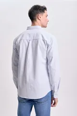 Camisa celeste a rayas verticales blancas, de corte clásico, con cuello abotonado, manga larga y bolsillo en el pecho.