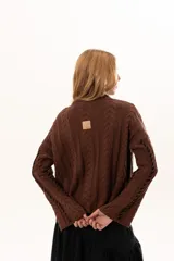 Buzo tejido de punto con silueta relajada, cuello alto y mangas tipo campana. Presenta un diseño de trenzas verticales con detalles de costuras en contraste a lo largo de la prenda.