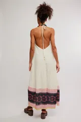 Vestido largo de tela liviana con estampado tipo patchwork de guardas florales en tonos negros, blancos y rosados, con escote en V profundo, tiras finas para anudar al cuello estilo halter y espalda descubierta.