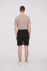 Bermuda de corte recto y diseño minimalista, confeccionada en tejido técnico de poliéster. Presenta cintura elástica con cierre de botón frontal, bolsillos laterales y un bolsillo pequeño adicional en el lateral izquierdo.