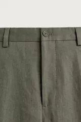 Pantalón de traje regular fit de lino color verde militar, con bolsillos laterales y bolsillos traseros de doble vivo con botón. Cierre frontal con cremallera y botón.
