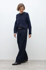 Pantalón de jean de corte wide leg en color azul oscuro, con tiro medio y cierre frontal con botón y cremallera.